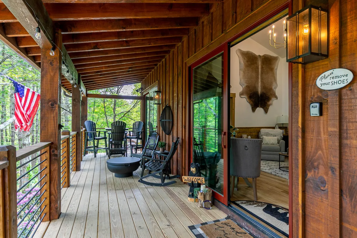 A welcoming outdoor setting with rocking chairs arranged around a fire pit, an American flag, and a prominent 'welcome' sign. The area conveys a sense of coziness and communal gathering, ideal for evening fireside chats and enjoying the outdoors together.