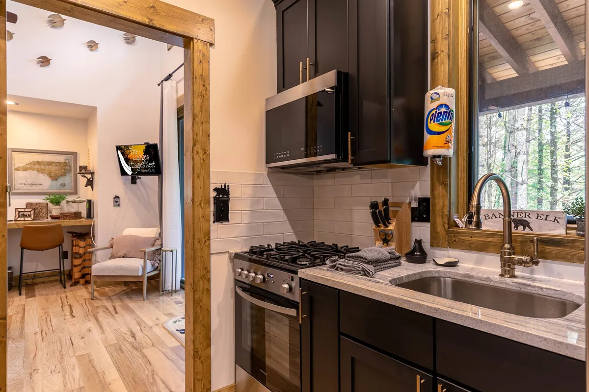 This image features a modern kitchen with up-to-date appliances, a granite countertop, wooden framing, and an open layout. The kitchen is bright and functional, clearly stocked for guests, and exudes a homey, welcoming vibe.