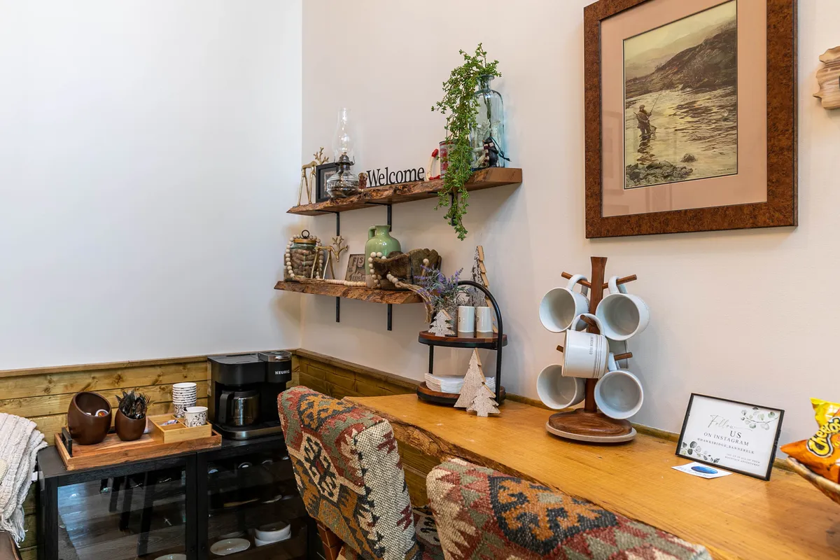 A warm, inviting entry area with a 'Welcome' sign, shelving adorned with decorative items, a convenient coffee station, and cheerful wall art. The space feels organized and ready for guests.